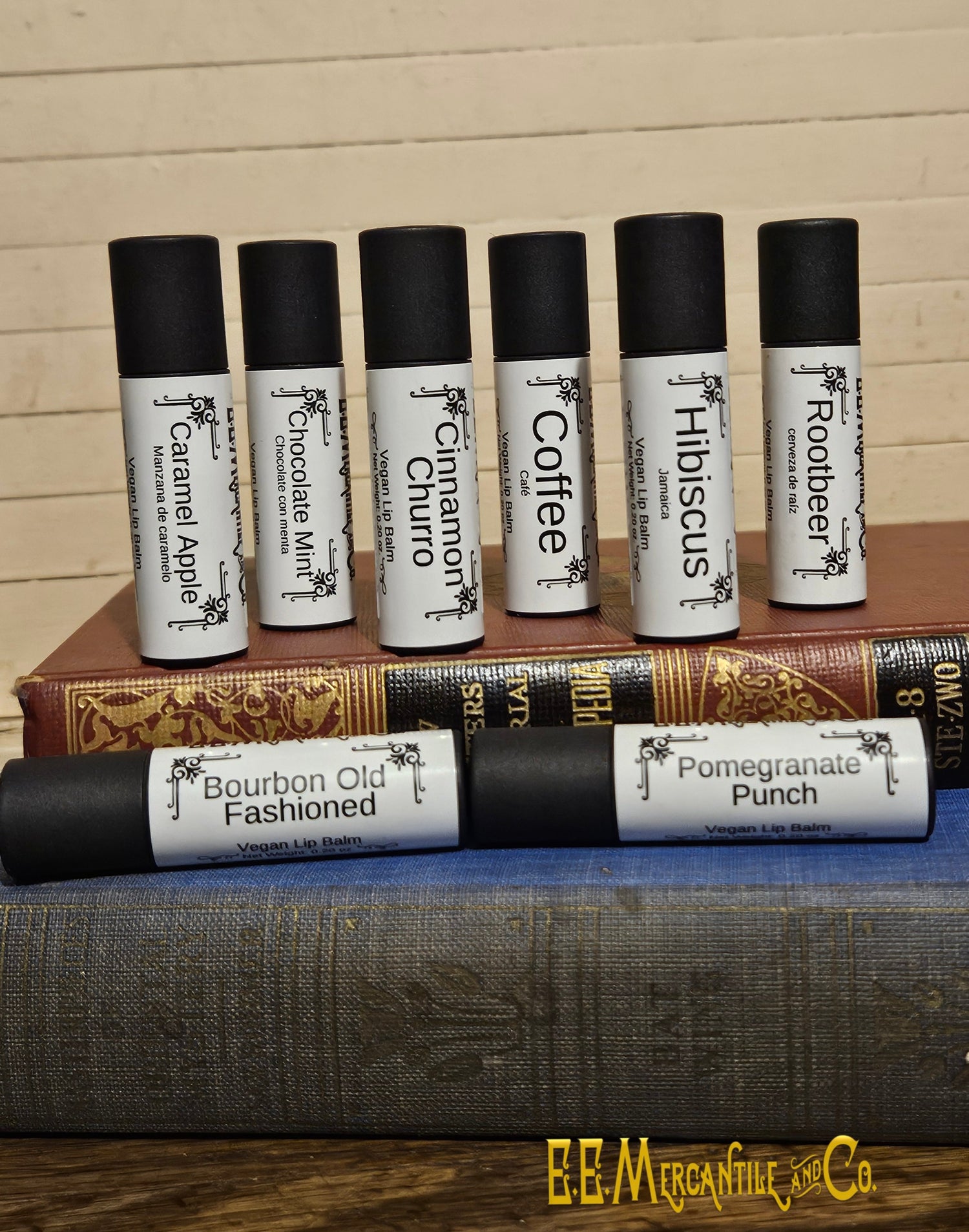 Assorted lip balms in black and white paper tubes arranged on top of two old books.