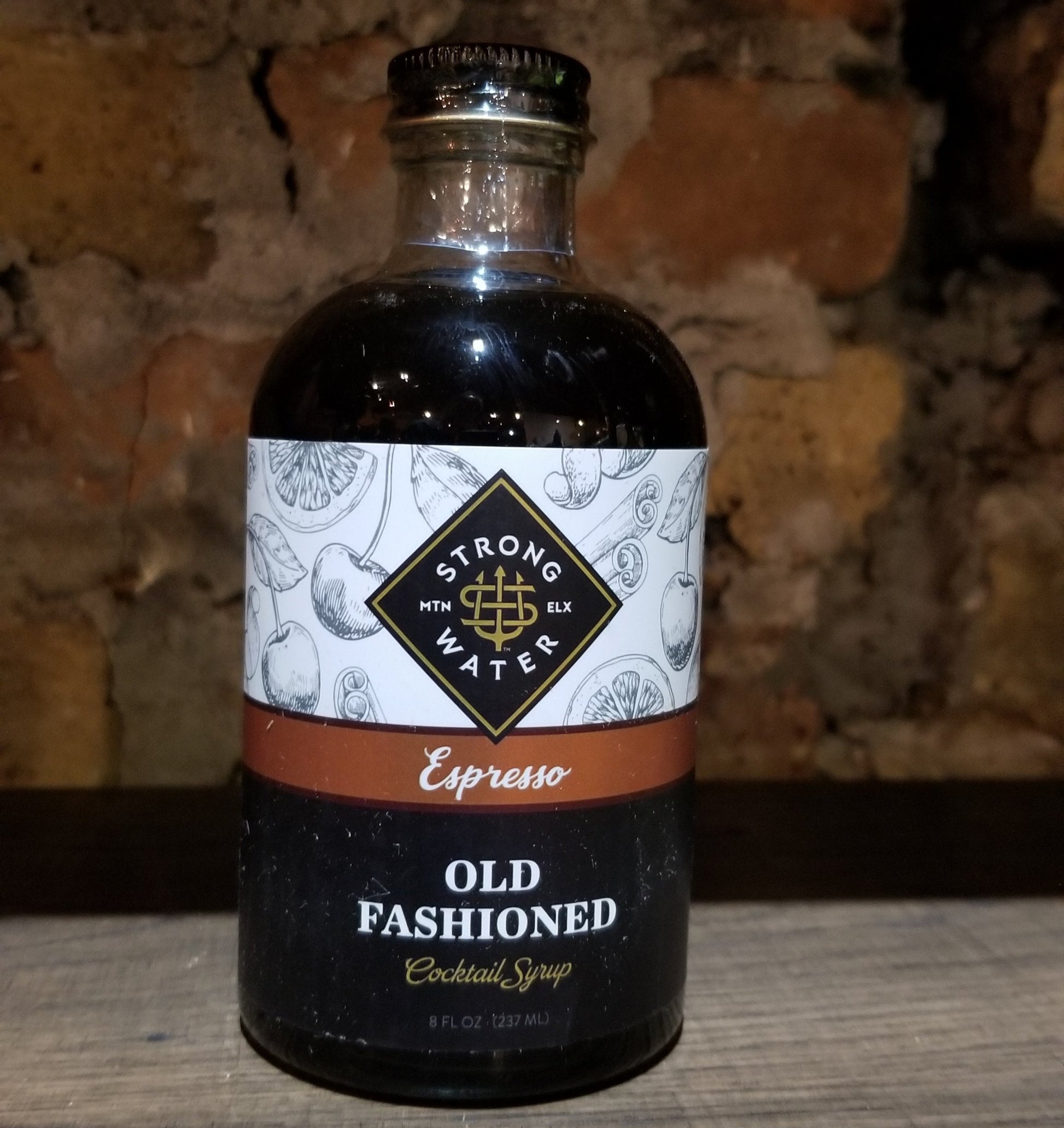 Bottle of Old Fashioned cocktail syrup with a label on a wooden surface.