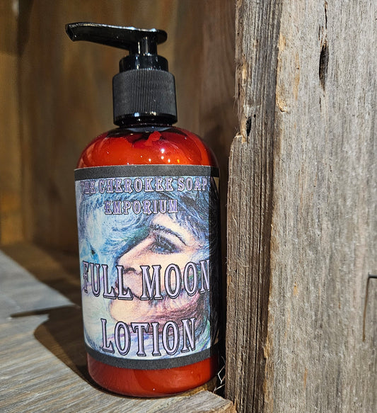 An amber plastic bottle with black pump top. Label is blue, black, peach with illustration of a moon woman. Bottle sits on reclaimed wooden shelf.