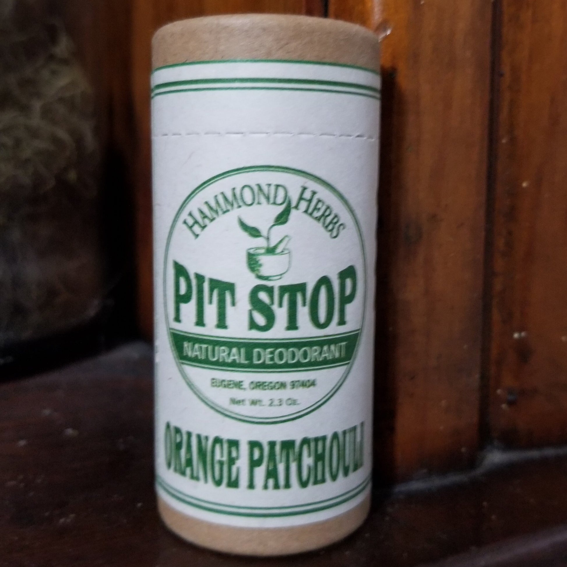 Close up of paper tube container with beige and green label. Background is wood.