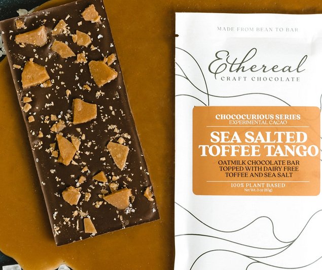 white wrapper with brand label sits alongside dark chocolate bar sprinkled with sea salt and big chunks of caramel brown toffee.