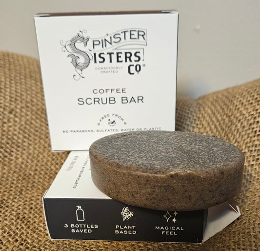 brown circle soap bar, covered in exfoliating coffee grounds, sitting on top of black and white box. Box reads, "3 Bottles saves, plant based, magical feel".