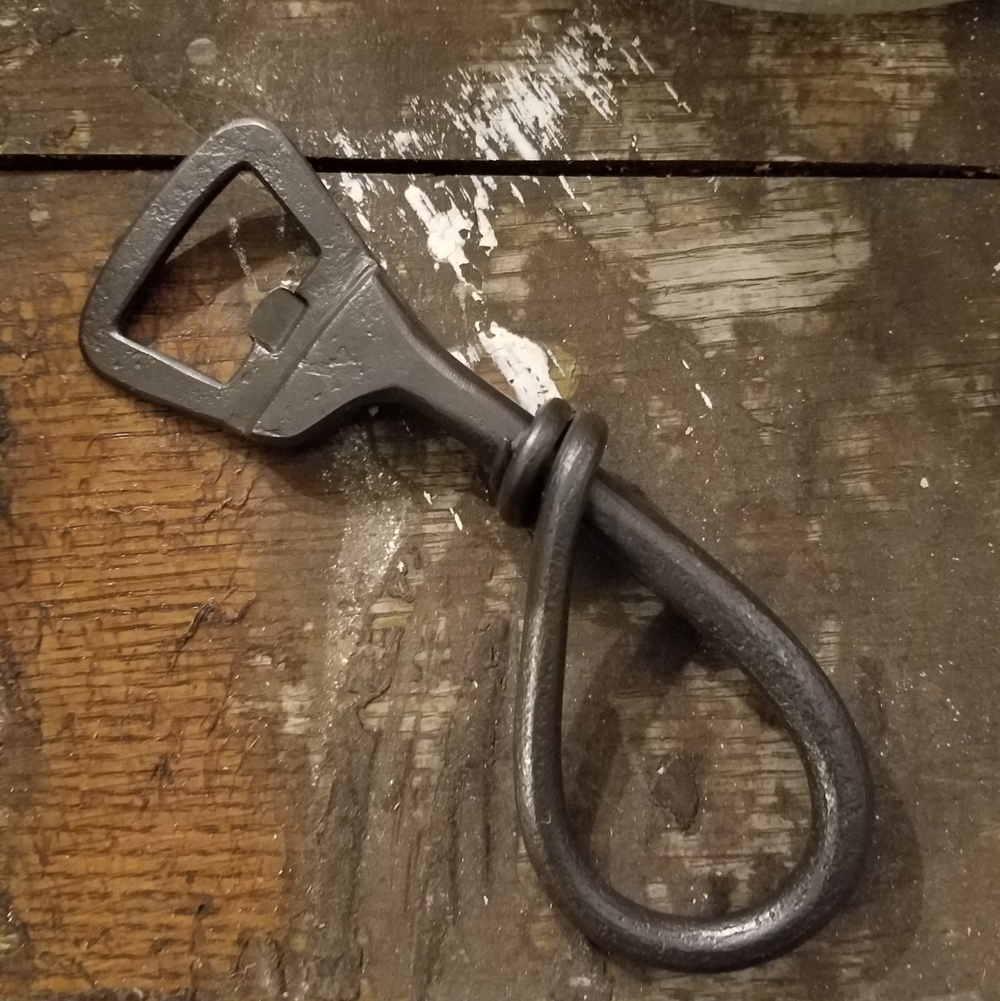 Hand forged steel bottle opener, wrapped in the center for right handed people.